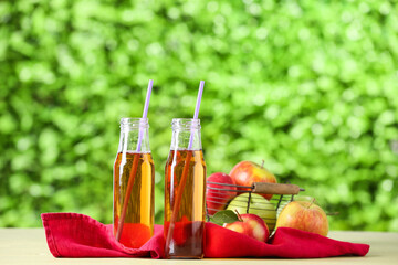 Bottles of tasty apple juice on table outdoors