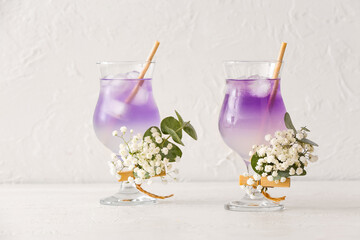 Glasses with tasty cocktail and beautiful gypsophila flowers on light background