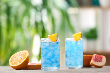 Glasses of Blue Lagoon cocktail on table outdoors, closeup