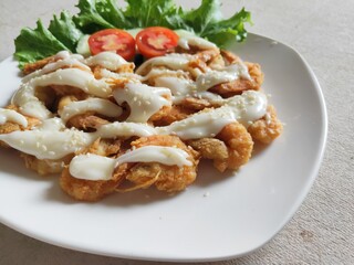 Fried shrimp butter with mayonnaise and Lettuce against a wooden background.