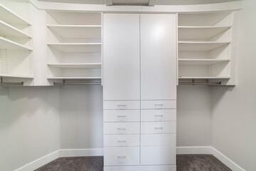 White windowless walk-in closet with tall cabinet in the middle