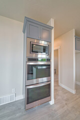 Built-in double oven and microwave on a wall with gray cabinet doors on top