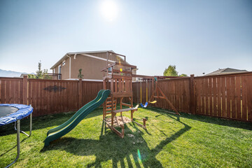 Wooden playground and trampoline at the backyard with lawn