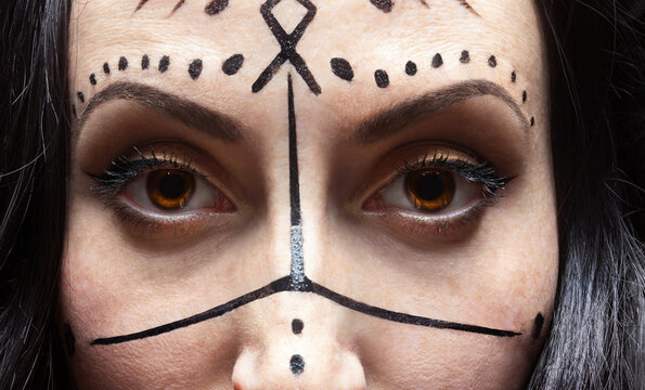 Сlose up face of mysterious woman with runic makeup.