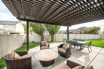 Woven armchairs with cushion and dining table under the pergola roof - obrazy, fototapety, plakaty