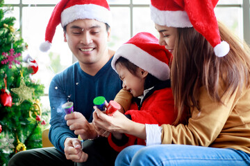 Happy Asian family father mother sitting on sofa helping afraid daughter wears sweater with red and...