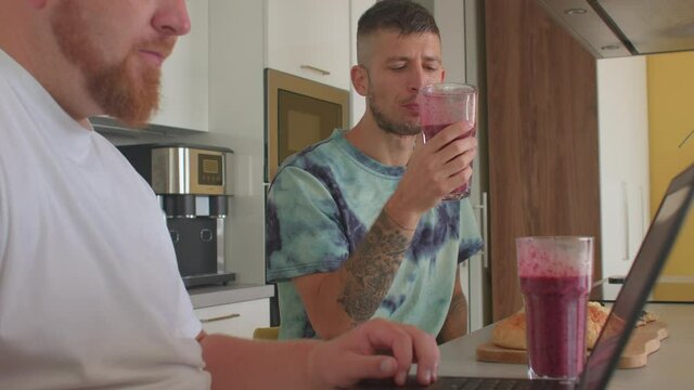 A young man drinks a delicious fruit smoothie during breakfast in the home kitchen. Vitamin diet to boost immunity. Eating for a healthy weight.