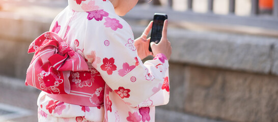 woman tourist wearing kimono take a photo by mobile smartphone in Kyoto, Japan. Asian girl in...