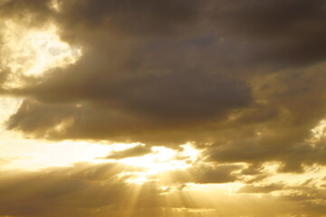 雲の隙間からもれるオレンジ色の太陽の光　天使の梯子