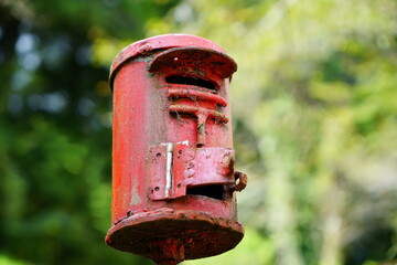 自然の中にあるホコリ汚れのある赤いポスト型灰皿　中央