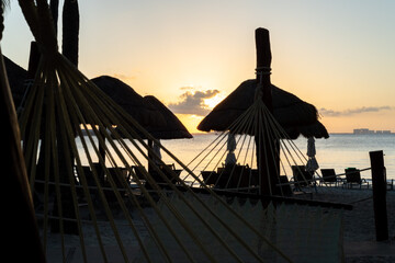 Sunset on beach  with silhouette of hammocks and umbrellas