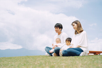 Fototapeta premium 空と芝生に座る家族・ファミリー（4人） 