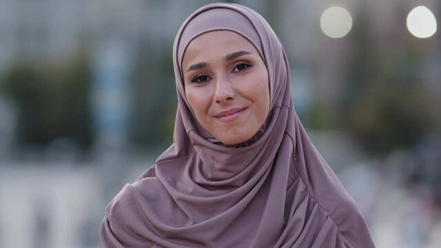 Close-up human female face portrait muslim girl young friendly smiling cute islamic woman student foreigner client wears hijab millennial arab lady standing outdoors looking at camera smile toothy