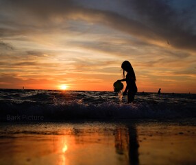 silhouette of a person walking on the beach at sunset