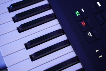 A black midi keyboard with black and white keys in a studio 