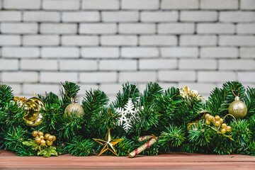 Pine tree branches with Christmas ornaments border, festive decoration for celabration, white brick wall blur background. Horizontal lay out, large copy space.