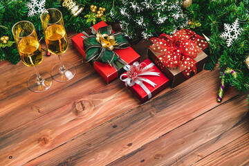 Fototapeta na wymiar Top view of Christmas new year celabration, chamange two glasses, gift boxes small pine tree decorate with christ ornaments at border. Lay on wood board background copy space