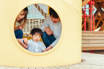 Obraz na płótnie Canvas 遊具で遊ぶ子供と両親 