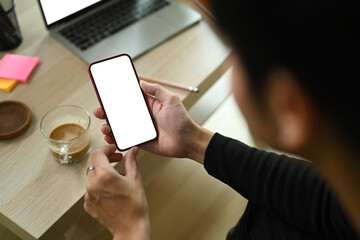 Young male using smart phone in living room.
