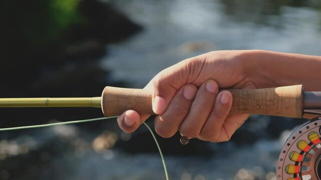 Close up of a young female asian hand stripping fly fishing line on a river