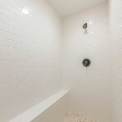 Square frame Inside a white shower room with tile flooring and walls