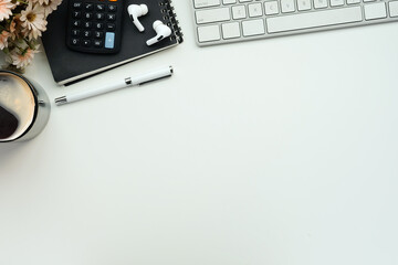 Coffee cup, earphones, calculator and notebook on white table, Top view.