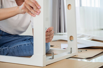 Man assembling white chair furniture at home