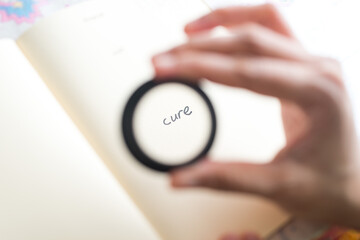 A magnifying concept for the word Cure on a paper