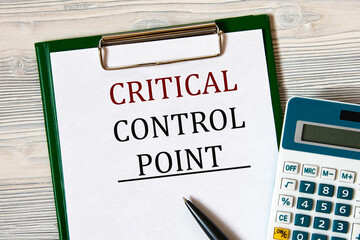 CRITICAL CONTROL POINT - words on a notebook on a light wooden background with a calculator and a...