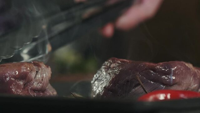Cooking meat on the grill. The chef turns juicy fresh beef filet mignon steaks with tongs in a hot frying pan. Fried meat in the restaurant kitchen. Cooking in the kitchen