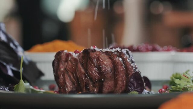 Close-up of Juicy fried beef steak filet mignon on a plate with herbs and spices sprinkled with salt. A delicious dish for dinner. Cooking meat on the grill.