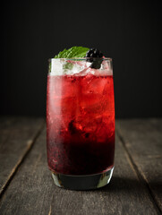 Blackberry cocktail with crushed ice on the rustic wooden background. Selective focus. Shallow depth of field.
