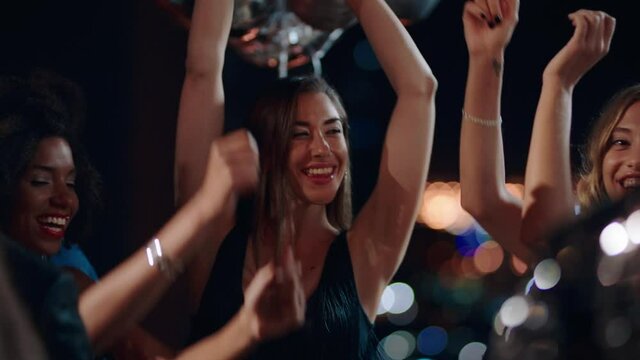 group of friends celebrating sexy women dancing enjoying glamorous new years eve party having fun celebration wearing stylish fashion at social gathering on rooftop at night 