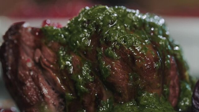 Close-up of juicy fried beef steak filet mignon on a plate with green herb sauce . A delicious dish for dinner. Cooking meat on the grill. Preparing food