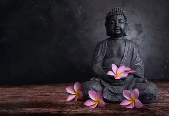 Poster Buddha statue with frangipani flowers on a dark background © Karneg
