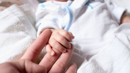 A 2-3 month old baby shakes his parents' hands.