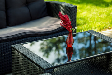 Seating area, sofa, coffee table, red vase with a flower. High quality photo