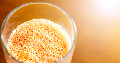 グラスに入った鮮やかなオレンジ系のスムージーの上からアップとコピースペース