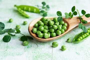 Fresh green peas pods and green peas with sprouts on green wooden background.
