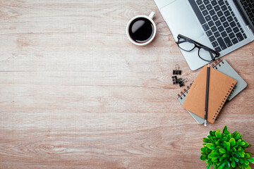 Work from home. desk office with laptop, blank notepad, coffee cup and pen on wood table. Flat lay top view copy spce.