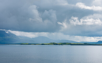 The island Videy seen from Reykjavik.  Sun is shining on the island in dramatic weather.