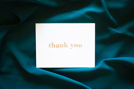 Thank you card on dark green silk background. Elegant luxury satin cloth pattern waves. High contrast. Special thank you note.