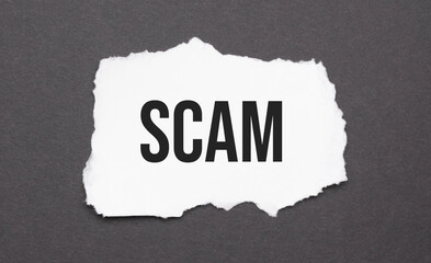 scam sign on the torn paper on the black background