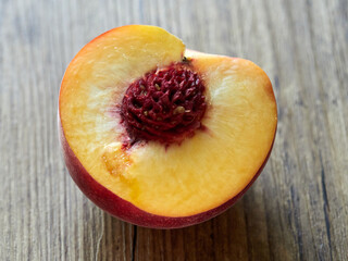 Half a peach lies on a wooden table
