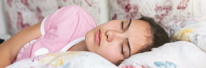 pretty schoolgirl sleeps in bed among blanket and pillows