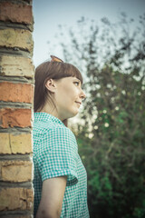 a brunette girl is standing against a brick wall