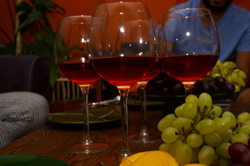 a fruit basket with full of green and red grapes, a wine bottle, a goblet on a woodden table