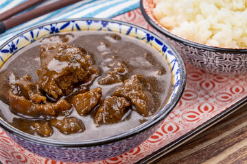 plat de morceaux de boeuf aux oignons et riz sur une table