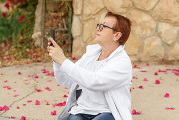 Senior Influencer using smart phone to take pictures. Baby boomer woman travels, making video vlog and using mobile phone.