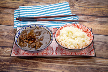 plat de morceaux de boeuf aux oignons et riz sur une table